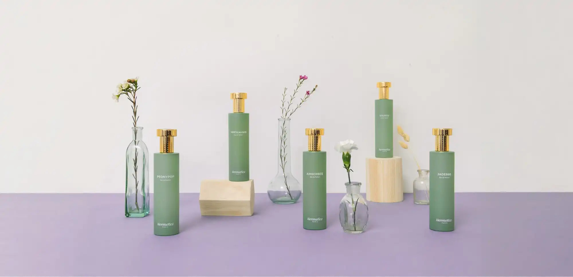 Green and beige cosmetic bottles with glass bud vases arranged in a minimalist display.